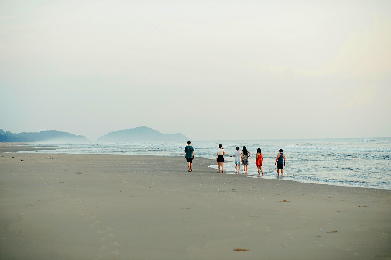 Personas caminando en la playa al atardecer, simbolizando la conexión, la calma y el proceso terapéutico