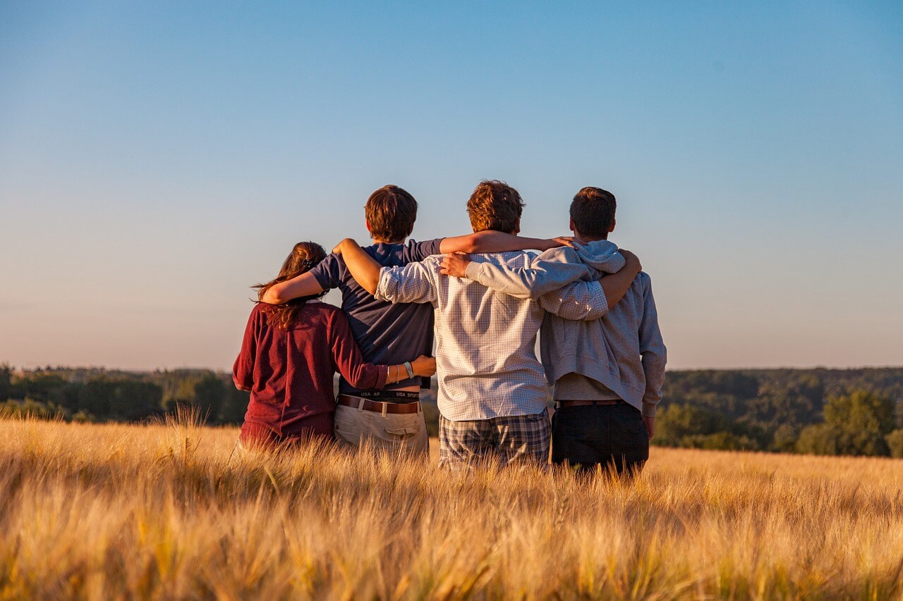 Personas abrazadas en un campo abierto, simbolizando amistad, conexión emocional y vínculos saludables.