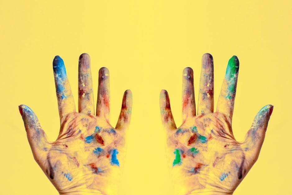 Colorful fingers spread against a bright yellow backdrop, showcasing creativity.